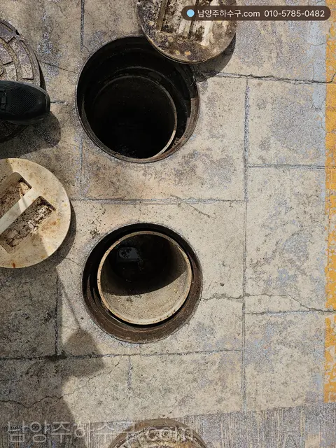 바닥 배수 소제구 두 곳의 뚜껑을 열어 놓은 상가 건물 현장
